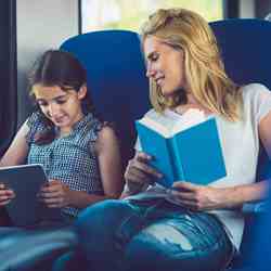 Kind met tablet en moeder met boek samen op de trein